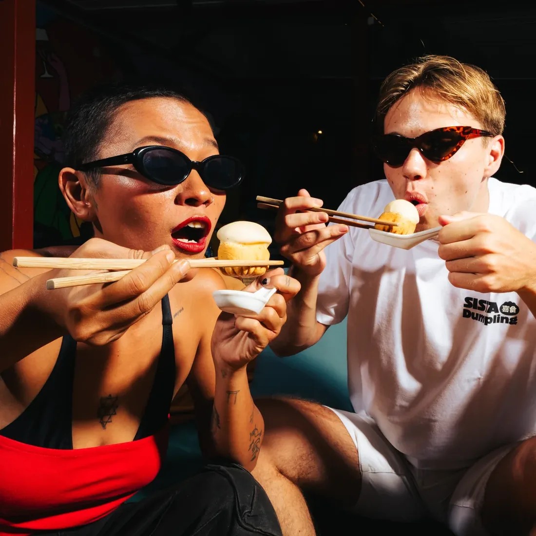 Two friends tucking into dumplings together at night